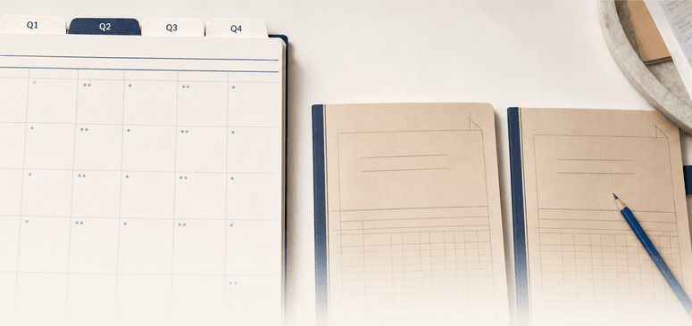 Overhead view of a quarterly planning calendar, two scenario notebooks, and orderly receipts on a warm white desk