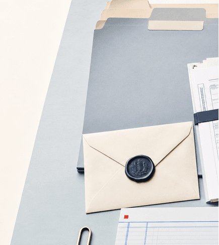 A sealed envelope, blank-tab folders, and an estate tax return packet arranged on a pale blue-gray desk